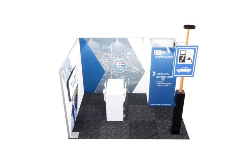 Exhibition stand Exhibition stand Design 145 has blue and white walls, a tall signpost in the form of an EV charging station, a white counter and digital displays with technology and future mobility as the theme - a presentation by expert stand construction.